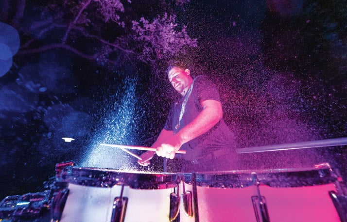 Percussionist playing drums with water splashing in the air