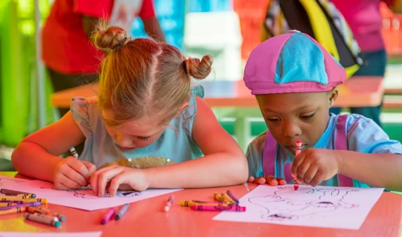 Two children coloring a sheet of paper