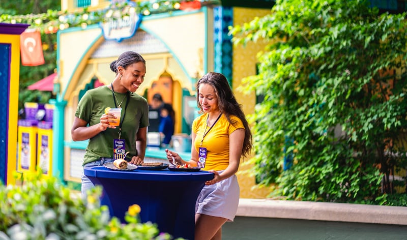 Two women at a cocktail table eating food