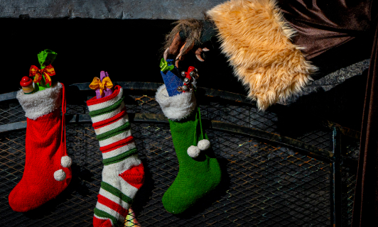 Three Christmas stockings with a creepy hand