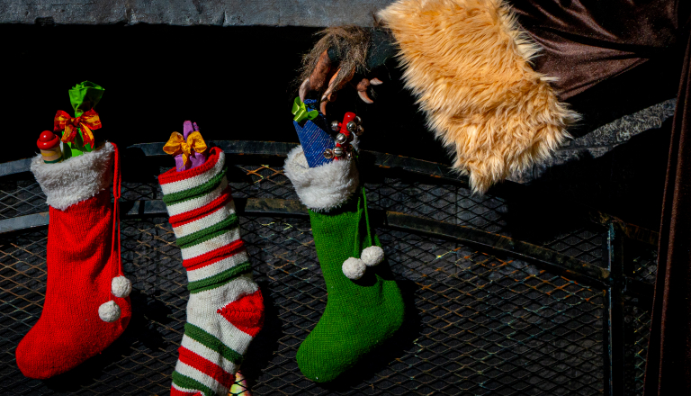 Three Christmas stockings with a creepy hand
