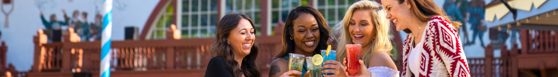 4 woman cheering with drinks in front of festhaus