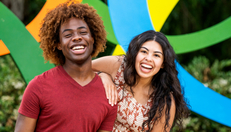 Two young adults in front of the Busch Gardens logo