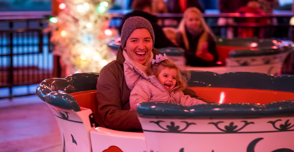 Woman and child in winter clothes riding a teacup ride