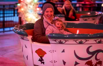 Woman and child in winter clothes riding a teacup ride