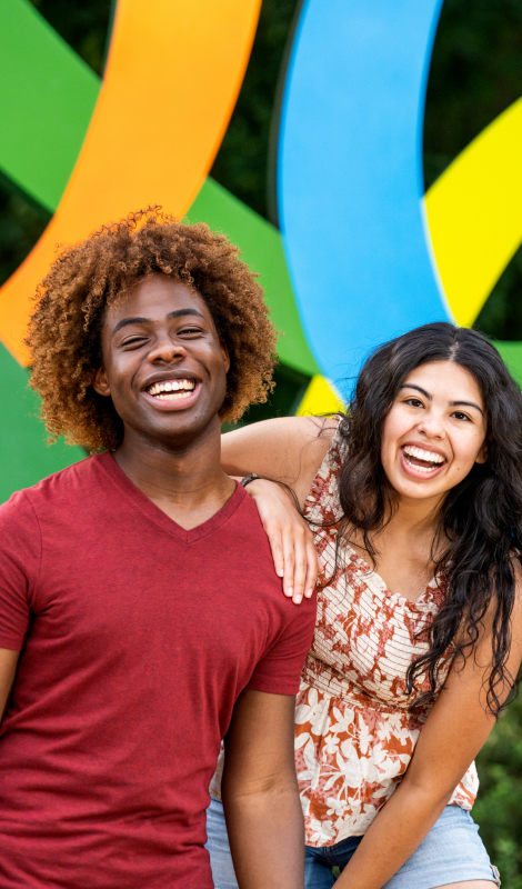 Two young adults in front of the Busch Gardens logo