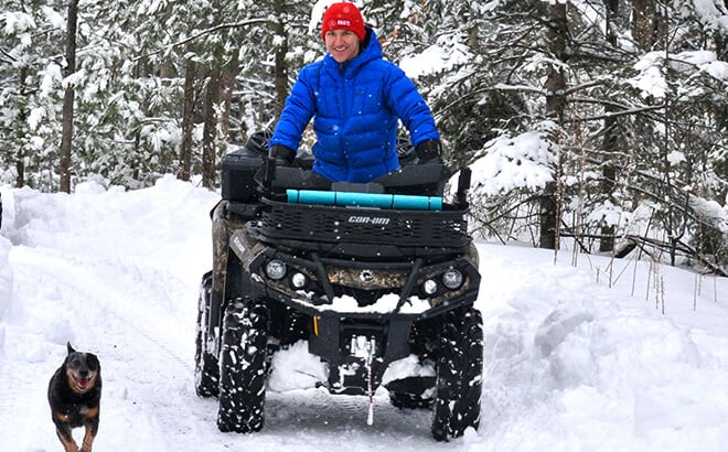 Elvis Stojko on four wheeler in winter with dog